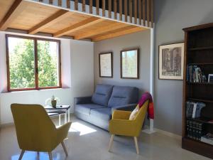 a living room with a blue couch and two chairs at Antiga Biblioteca in Solsona