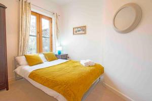 een slaapkamer met een bed met gele lakens en een raam bij Oxford CityCenterTrainStation two bedroomApartment in Oxford