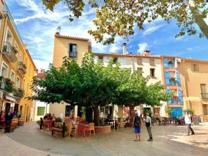 a group of people standing around a tree in a street at Maison de FLO Centre Historique Argeles sur mer in Argelès-sur-Mer