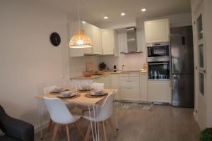 a kitchen with a table and white cabinets and appliances at Modern Apartament al costat del Parc de la Devesa in Girona
