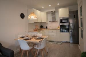 una cocina con mesa y armarios y electrodomésticos blancos en Modern Apartament al costat del Parc de la Devesa, en Girona