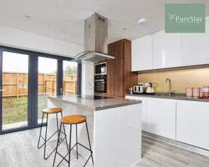 a kitchen with white cabinets and bar stools at Perfect for Business Stays in Manchester - 5 Bedroom House By PureStay Short Lets & Serviced Accommodation in Manchester