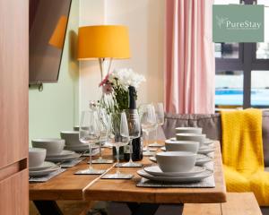 - une table avec des plats blancs et des verres à vin dans l'établissement Perfect for Business Stays in Manchester - 5 Bedroom House By PureStay Short Lets & Serviced Accommodation, à Manchester