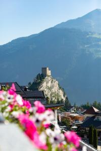 un castillo en la cima de una montaña con flores rosas en Apart-Pension Bergland en Ladis