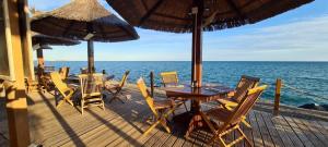 een houten terras met een tafel en stoelen en de oceaan bij Bungalow de 3 chambres avec piscine partagee et terrasse a Vias a 1 km de la plage in Vias