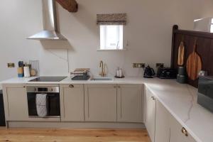 a white kitchen with a sink and a stove at Luxury Victorian Hayloft barn self contained in South Witham