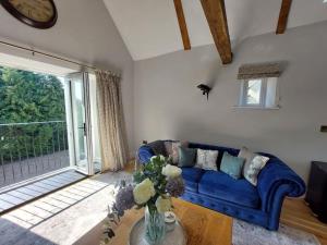 a living room with a blue couch and a large window at Luxury Victorian Hayloft barn self contained in South Witham