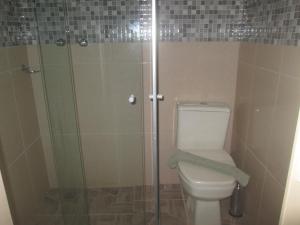 a bathroom with a toilet and a glass shower at Recanto das Rosas in Poços de Caldas