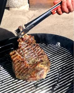 a steak being grilled on a grill with a spatula at Chez ROMU in Rieutort