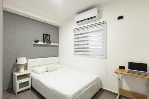 a white bedroom with a bed and a window at Oazis 1BR Apt,Central Old Town, Great location in Beer Sheva