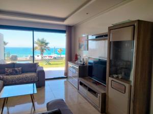 a living room with a flat screen tv and a living room at Appartement Plage des Nations Prestigia Front Mer avec grand Jardin in Sidi Bouqnadel