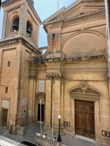 ein altes Gebäude mit einem Uhrturm und einer Tür in der Unterkunft 15 Main Gate in Vittoriosa