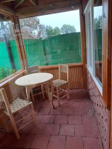 un porche cubierto con mesa y sillas en Hotel Artesanos, en Villa Alegre
