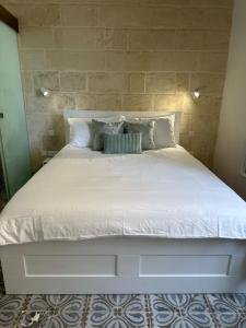 a large bed with white sheets and pillows at 15 Main Gate in Birgu