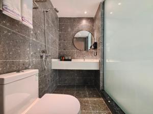 La salle de bains est pourvue de toilettes, d'un lavabo et d'un miroir. dans l'établissement Holiday Inn Guoshang, à Jianyang