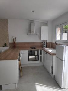 une cuisine avec des armoires blanches et un comptoir en bois dans l'établissement Maison indépendante avec terrasse, jardin & parking privé, à Hérépian