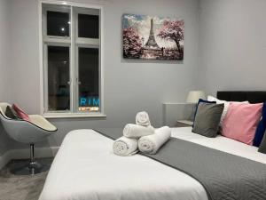 1 dormitorio con 2 camas, toallas y silla en Modern & Spacious 2 bed Apartment at Addison Court - Sleeps 6, Free WIFI, en Watford