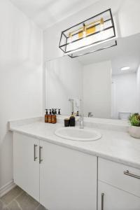 a white bathroom with a sink and a mirror at Barrie Luxe, Pool Table 6 BR 6 BA Custom Design A+ Location in Barrie