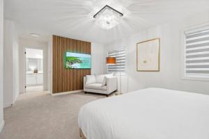 a white bedroom with a bed and a chair at Barrie Luxe, Pool Table 6 BR 6 BA Custom Design A+ Location in Barrie