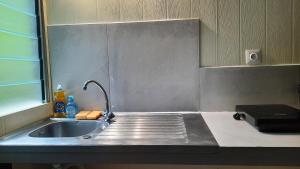 a kitchen counter with a sink and a stove at Vaiterupe Sweet Home in Orufara