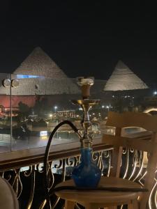 un jarrón azul sobre una mesa en un balcón con pirámides en Unique Pyramids View INN en El Cairo