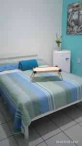 uma cama com um banco de madeira em cima em Hospedaria FOR755 em Fortaleza