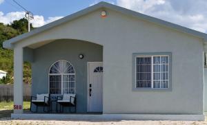 a small white building with a door and chairs in it at Sanel’s Luxury Stay in Discovery Bay