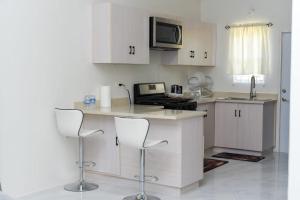 a kitchen with white cabinets and a counter with stools at Sanel’s Luxury Stay in Discovery Bay