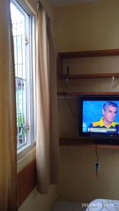 uma televisão sentada numa prateleira ao lado de uma janela em Hospedaria FOR755 em Fortaleza