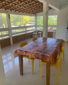 a wooden table and chairs in a room with windows at Porto Colore praça Sete in Porto De Galinhas