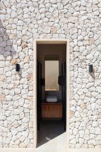 a stone wall with a mirror in a hallway at Akbal Tulum in Tulum