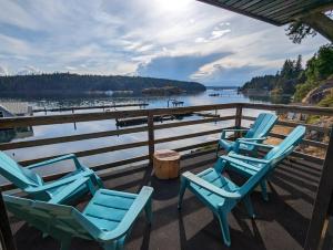 a group of chairs sitting on a deck overlooking a body of water at Jade Resort-Oceanfront Suites in Gowlland Harbour in Heriot Bay