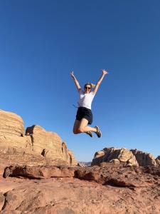 een vrouw die in de lucht springt boven enkele rotsen bij Wadi Rum Camp in Wadi Rum +58 foto's