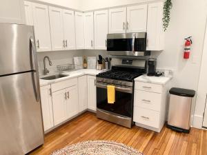 uma cozinha com armários brancos e electrodomésticos de aço inoxidável em Charming 1BD/1BA Studio; walk to stadiums & UMD em Baltimore