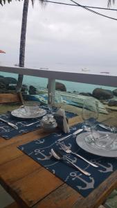 a table with plates and silverware on top of a table at Encanto do Mar in Praia de Araçatiba