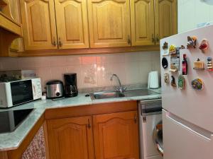 - une cuisine avec des placards en bois et un réfrigérateur blanc dans l'établissement RELAX en SANTA POLA, ALICANTE, à Santa Pola