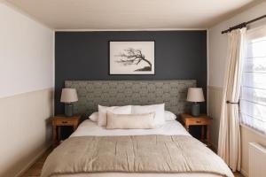 1 dormitorio con 1 cama grande y 2 mesitas de noche en Bories - Boutique Guest House, en Puerto Natales