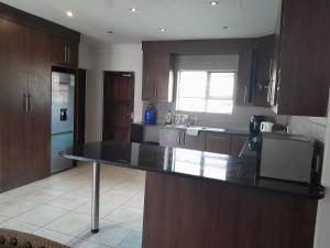 a kitchen with wooden cabinets and a black counter top at Secunda BackPackers in Secunda