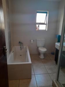 a bathroom with a tub and a toilet and a sink at Secunda BackPackers in Secunda