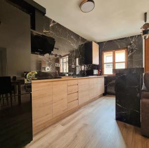 Una cocina con gabinetes de madera y paredes de mármol negro. en Vivienda Plaza Mayor, en León 4 fotos más