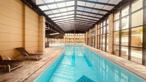 a large swimming pool in a building with windows at Suítes Inside Hotel Pinheiros in São Paulo