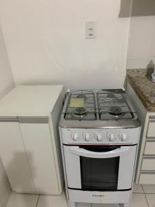 a kitchen with a stove in a white kitchen at Mont Carmelo Residencial Ap 5A Rede Tonziro in Porto Seguro