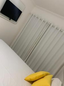 uma almofada amarela sentada numa cama num quarto em Mont Carmelo Residencial Ap 5A Rede Tonziro em Porto Seguro