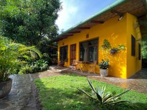 a yellow house with a table and chairs in a yard at Casa Única - Room with breakfast or Cabins with kitchen in La Laguna