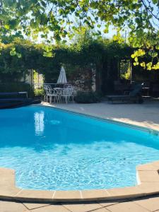 una gran piscina azul con mesa y sombrilla en Fabulous 2 bed Gite 2km quiet Walk into Eymet, en Eymet