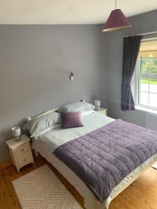 a bedroom with a bed with a purple comforter and a window at Garrenmore Lodge B&B in Tipperary