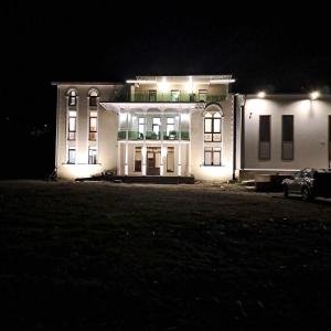 ein großes weißes Gebäude in der Nacht mit Lichtern in der Unterkunft Gonadze Vineyards Hotel in Ambrolauri