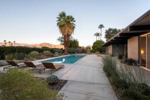 a swimming pool in a yard with chairs and a house at The Milky Way Modern Desert Retreat in Borrego Springs