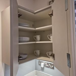 a cupboard with bowls and dishes in it at Delightfully & Spacious Guest House in Farnworth in Farnworth