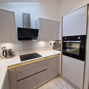 una cocina con armarios blancos y un aparato negro en Delightfully & Spacious Guest House in Farnworth, en Farnworth